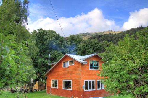 a house in a field with mountains in the background at Turismo Rural Los Alpes in Futaleufú