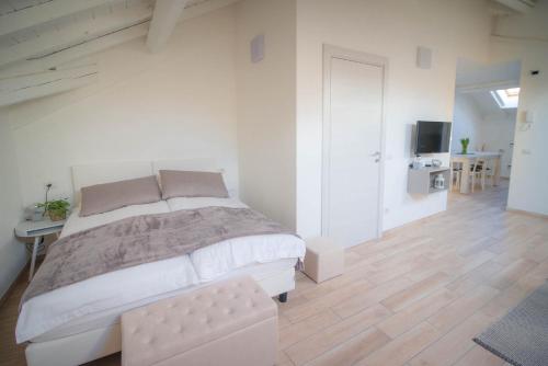 a white bedroom with a large bed and a wooden floor at Comonfive Apartments in Como
