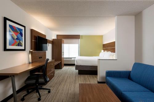 ein Hotelzimmer mit einem Schreibtisch und einem Bett sowie einem Zimmer in der Unterkunft Holiday Inn Express Hotel & Suites Charlotte Airport-Belmont, an IHG Hotel in Belmont