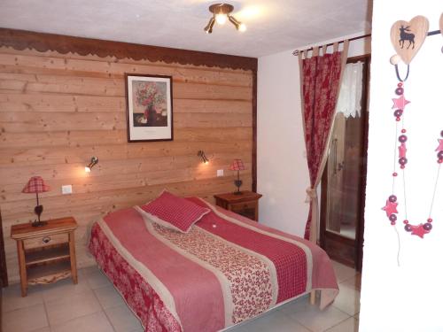 a bedroom with a bed and a wooden wall at Chalet Le Tredard in Feissons-sur-Salins