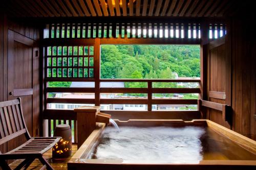 a hot tub in a room with a large window at Onyado Tsutaya in Kiso