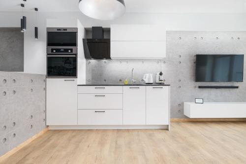 a kitchen with white cabinets and a flat screen tv at Venezia Apartment in Poznań