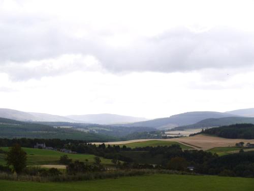 a view of a green field with mountains in the distance at Cardhu Country House in Aberlour