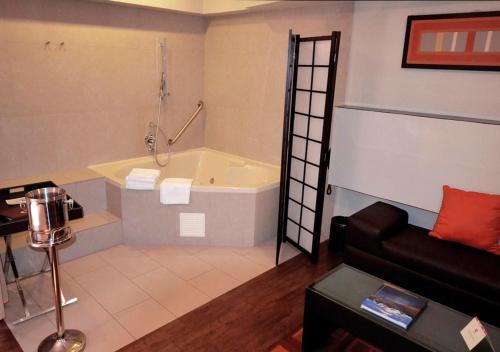 a bathroom with a bath tub and a couch at qp Hotels Lima in Lima