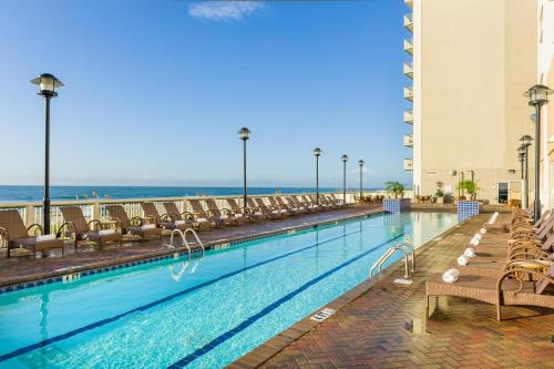 a swimming pool with chairs and the ocean in the background at Westgate Myrtle Beach Oceanfront Resort in Myrtle Beach