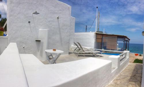 a white building with a table and a chair at Traditional House by the Sea in Mandrakia