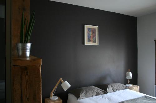 a bedroom with a black wall with a bed and a lamp at Chambre d'hôtes La Font in Eygliers