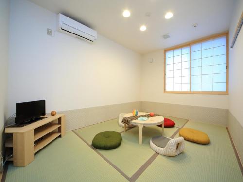 a living room with a tv and a table at Kamon Inn Hieijocho in Kyoto