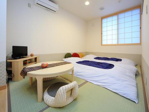 a room with two beds and a table and a desk at Kamon Inn Hieijocho in Kyoto