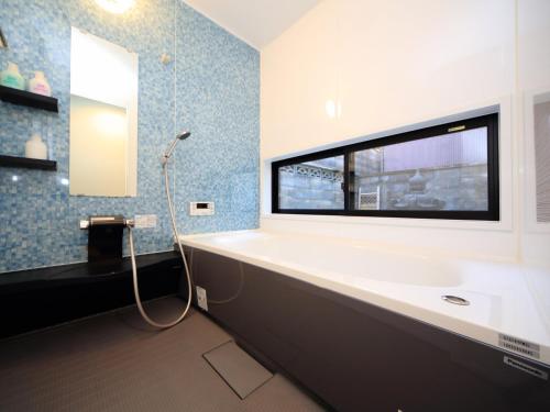 a bathroom with a tub and a sink and a mirror at カモンイン 稲荷 in Kyoto