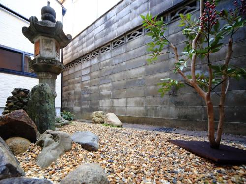 a garden with a fountain and a tree in front of a building at カモンイン 稲荷 in Kyoto