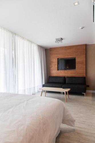 a bedroom with a bed and a couch and a tv at 2122 Hotel Art Design in Punta del Este