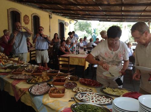a group of people standing around a table full of food at Agriturismo Borgo San Nicolao in Randazzo