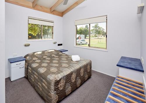 um quarto com uma cama e uma janela em Canton Beach Holiday Park em Toukley