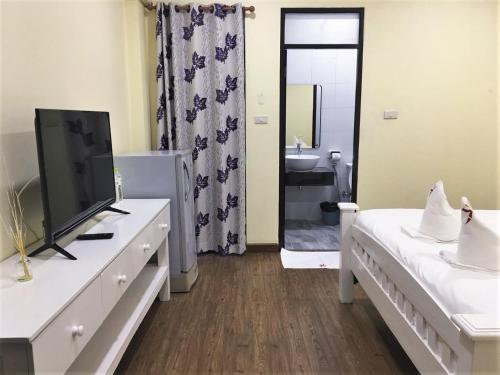 a bedroom with a tv and a bed and a bathroom at Kristi House in Chiang Mai