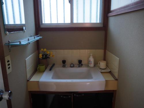 a white sink in a bathroom with two windows at Daikokuya Mt.Fuji in Fujiyoshida