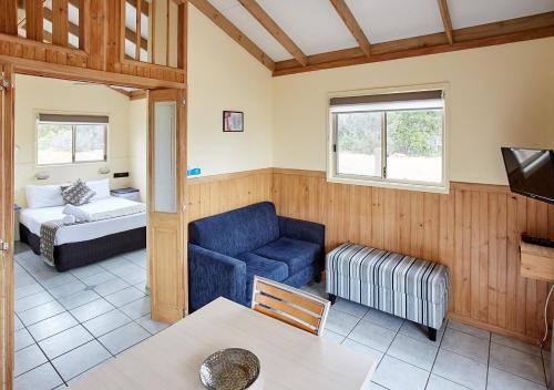 sala de estar con silla azul y sofá en Norah Head Holiday Park en Toukley