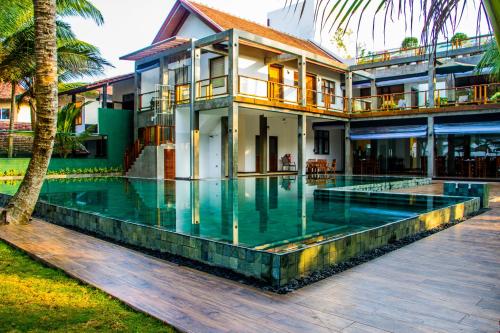 a house with a swimming pool in front of it at Hikka Sands & SPA in Hikkaduwa