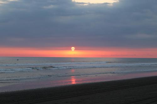 a sunset on the beach with the sun setting at Miguel Surf Camp in Quepos