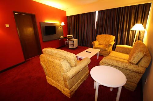 a living room with two chairs and a tv at Grand Riverview Hotel in Kota Bharu
