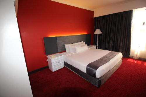 Habitación de hotel con cama y pared roja en Grand Riverview Hotel, en Kota Bharu
