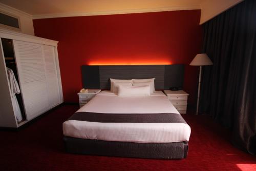 a bedroom with a large bed with a red wall at Grand Riverview Hotel in Kota Bharu