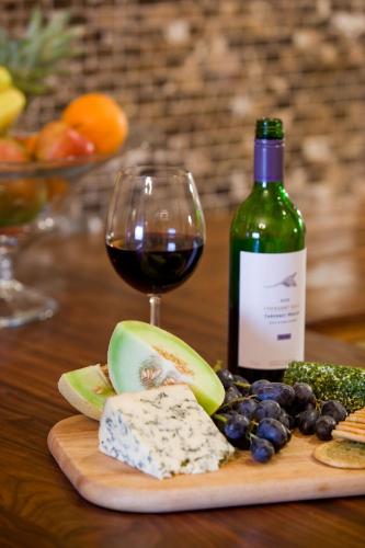 a bottle of wine and a glass of cheese and grapes at Portland Apartments in Cheltenham