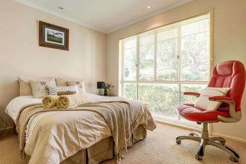 a bedroom with a bed and a red chair at Casa Al Lago in Montville