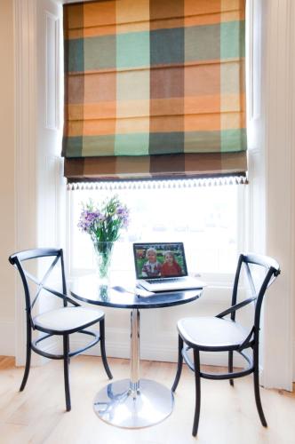 a table with two chairs and a laptop in a window at Portland Apartments in Cheltenham