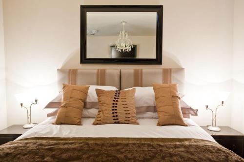 a bedroom with a bed with a mirror and pillows at Portland Apartments in Cheltenham