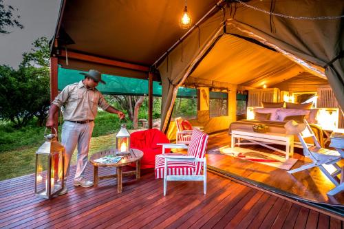 a man standing on a wooden deck with a tent at Flameback Eco Lodge in Tissamaharama