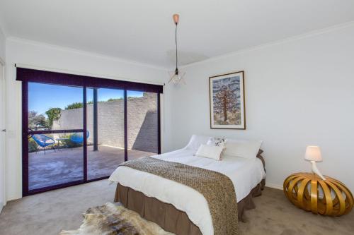 a bedroom with a bed and a large window at STYLISH, SUN-DRENCHED AND SOPHISTICATED in Inverloch