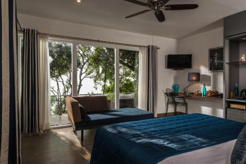 a bedroom with a bed and a large window at Cintacor Island Resort in Kārwār