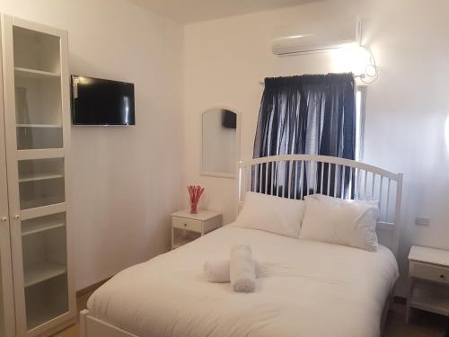 a bedroom with a bed with white sheets and a window at אבני החושן- Avnei Hoshen in Nahariyya