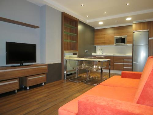 a living room with a television and a kitchen at Apartamentos Clarín in Oviedo