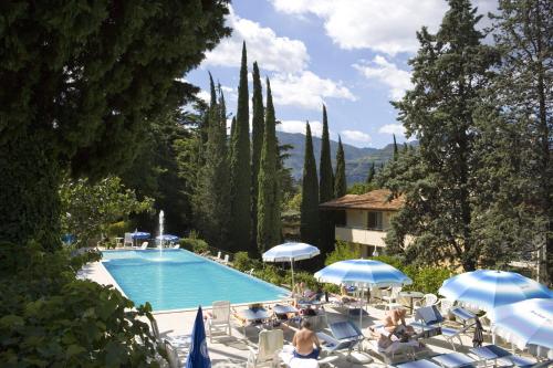 a swimming pool with chairs and umbrellas next to a building at Beach Hotel Du Lac Malcesine in Malcesine