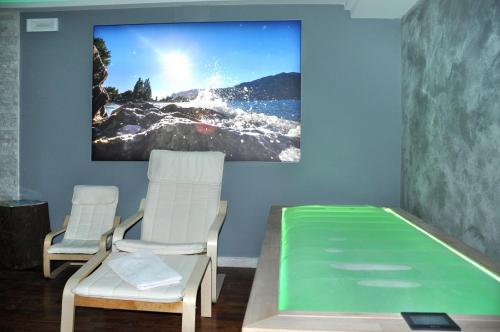 a room with two white chairs and a tv on the wall at Beach Hotel Du Lac Malcesine in Malcesine