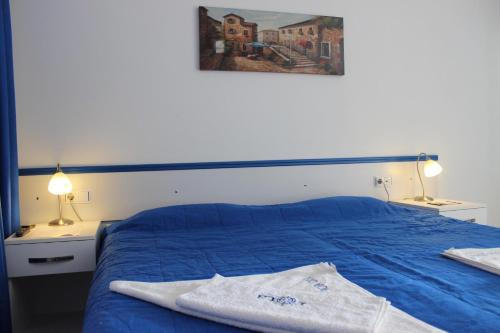 a bedroom with a blue bed with two lamps and a painting at Rota Hotel in Dalyan
