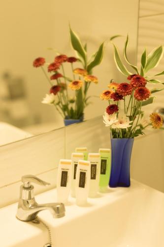 a bathroom sink with a mirror and a vase with flowers at Shalom Residence Nawala in Colombo