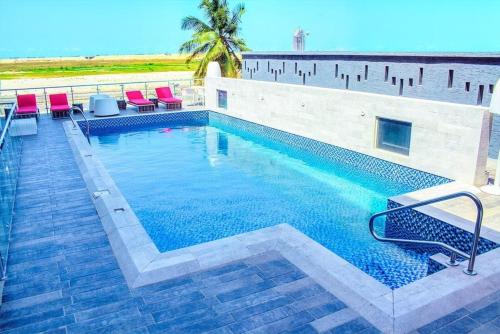 a large swimming pool with red chairs and the ocean at BWC Hotel in Lagos