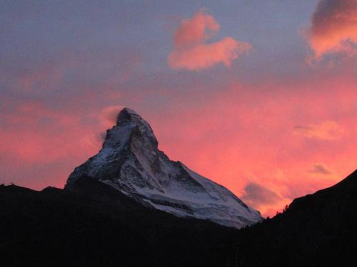 einen verschneiten Berg mit Sonnenuntergang im Hintergrund in der Unterkunft Artist Apartments & Hotel Garni in Zermatt