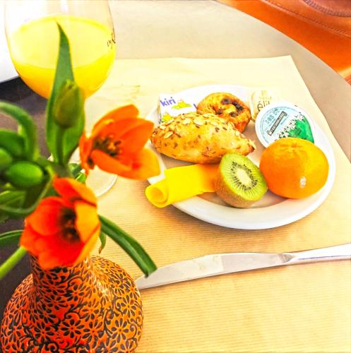 a plate of food on a table with fruit and a vase at Hotel Mille Colonnes in Leuven