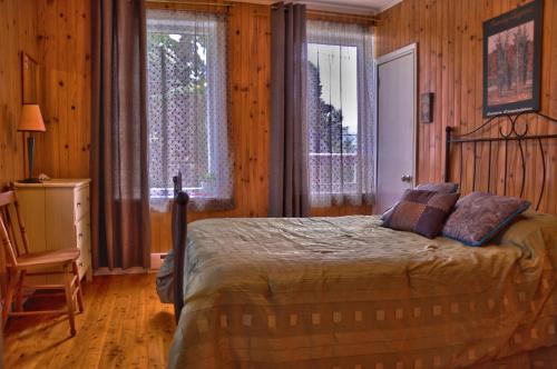 a bedroom with a bed in a room with wooden walls at Gîte TerreCiel in Baie-Saint-Paul