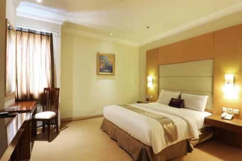 a hotel room with a bed and a desk at Coins Hotel Jakarta in Jakarta