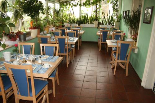a dining room with tables and chairs and plants at Hotel am Schloss Borbeck in Essen