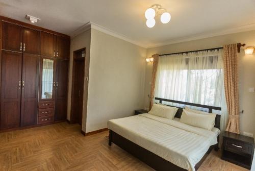 a bedroom with a large bed and a window at Ibis Apartments in Kampala