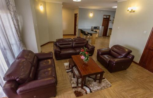 a living room with leather furniture and a table at Ibis Apartments in Kampala