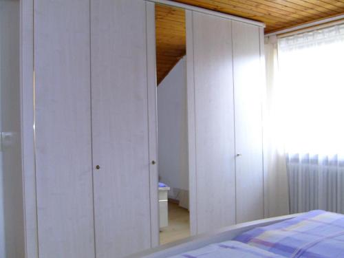 グラフェナウにあるFerienwohnung Pinkerの白いキャビネットとベッド付きのベッドルーム1室