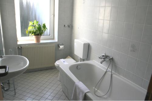 a bathroom with a tub and a toilet and a sink at Hotel am Schloss Borbeck in Essen