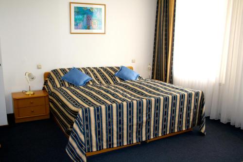 ein Schlafzimmer mit einem Bett mit blauen Kissen darauf in der Unterkunft Hotel am Schloss Borbeck in Essen